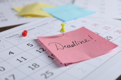 Photo of Sticky note with word Deadline and calendar on table, closeup