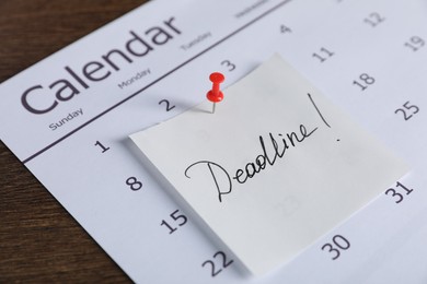 Photo of Sticky note with word Deadline and calendar on wooden table, closeup