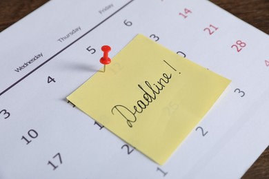 Photo of Sticky note with word Deadline and calendar on table, closeup