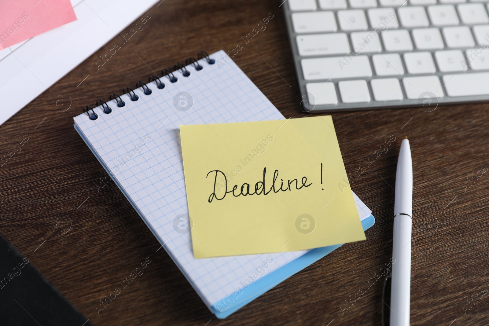 Sticky note with word Deadline, notebook, pen and computer keyboard on wooden table, closeup Photo of Sticky note with word Deadline, notebook, pen and computer keyboard on wooden table, closeup