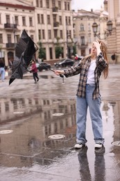 Photo of Woman with broken umbrella on city street