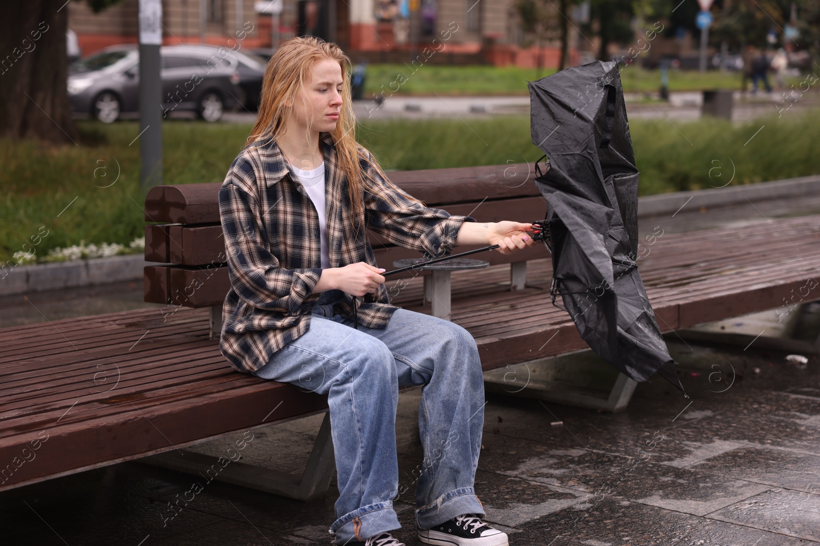 Woman with broken umbrella on bench outdoors Photo of Woman with broken umbrella on bench outdoors