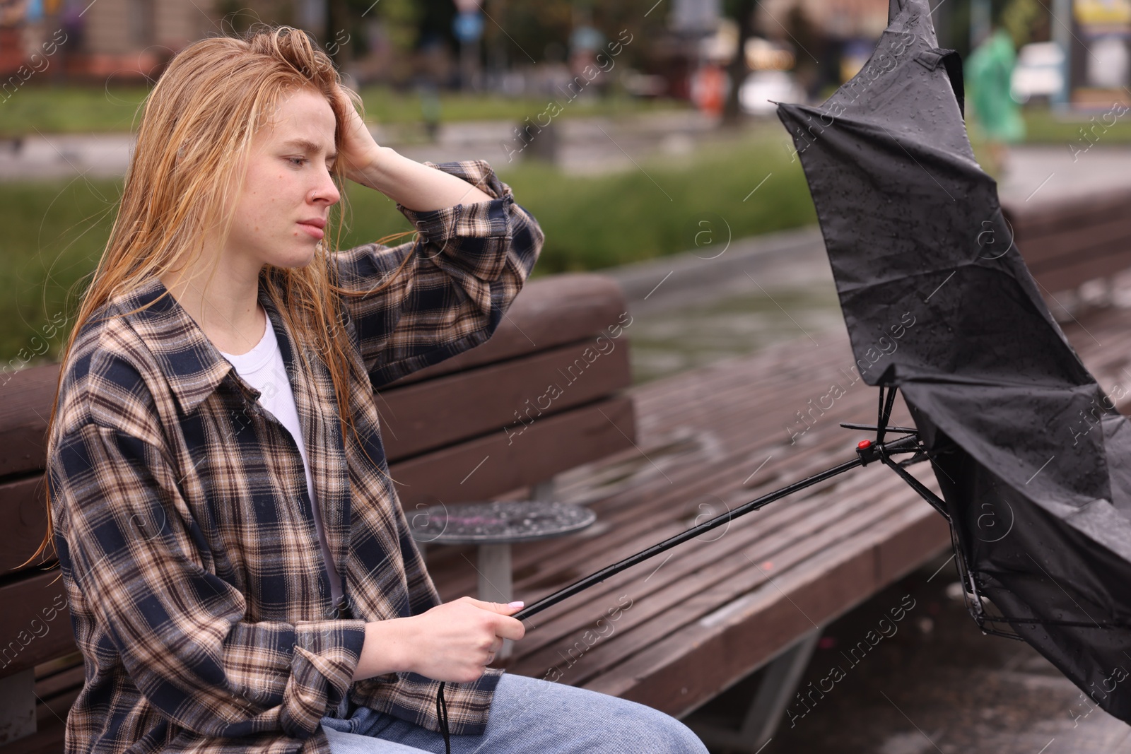 Frustrated woman with broken umbrella on bench outdoors Photo of Frustrated woman with broken umbrella on bench outdoors