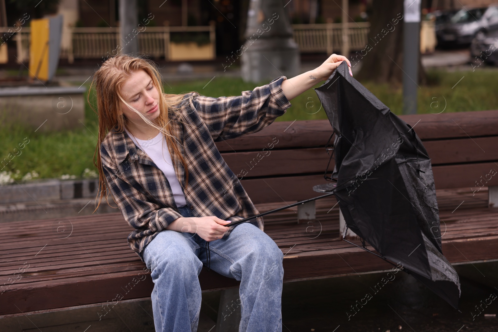 Woman with broken umbrella on bench outdoors Photo of Woman with broken umbrella on bench outdoors