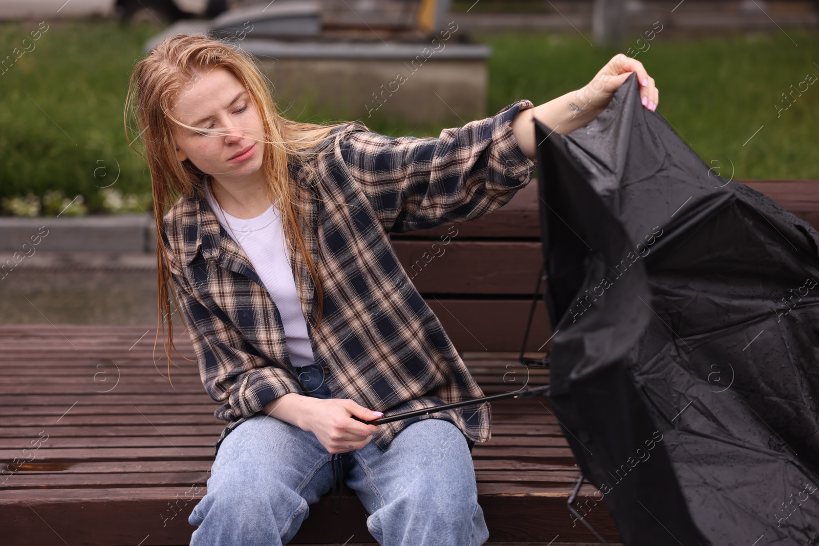 Woman with broken umbrella on bench outdoors Photo of Woman with broken umbrella on bench outdoors