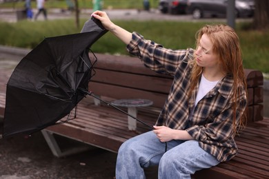 Photo of Woman with broken umbrella on bench outdoors