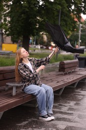 Photo of Woman with broken umbrella on bench outdoors