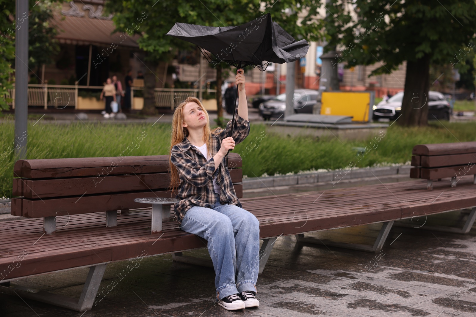 Woman with broken umbrella on bench outdoors Photo of Woman with broken umbrella on bench outdoors