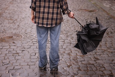Photo of Woman with broken umbrella on wet pavement outdoors, closeup