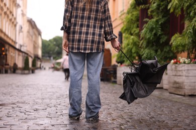 Photo of Woman with broken umbrella on wet pavement outdoors, closeup