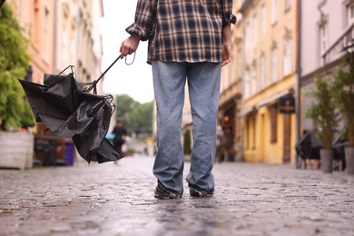 Photo of Woman with broken umbrella on wet pavement outdoors, closeup