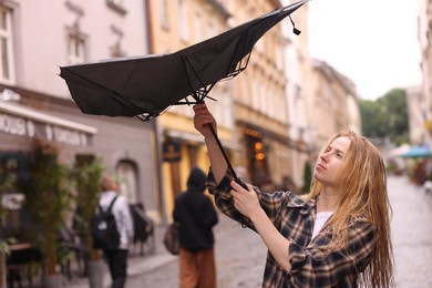 Photo of Woman with broken umbrella on city street