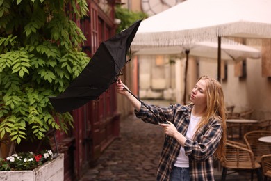 Photo of Woman with broken umbrella on city street