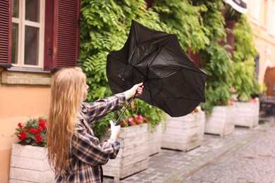 Photo of Woman with broken umbrella on city street