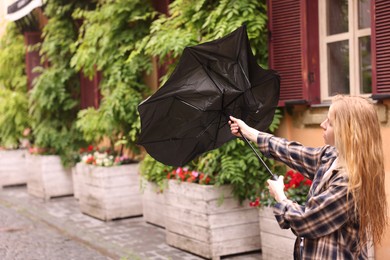Photo of Woman with broken umbrella on city street