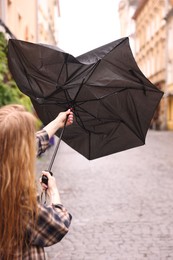 Photo of Woman with broken umbrella on city street, closeup