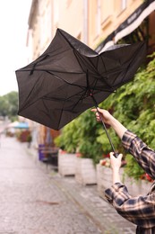 Photo of Woman with broken umbrella on city street, closeup