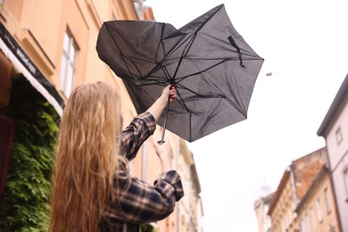 Photo of Woman with broken umbrella outdoors, low angle view