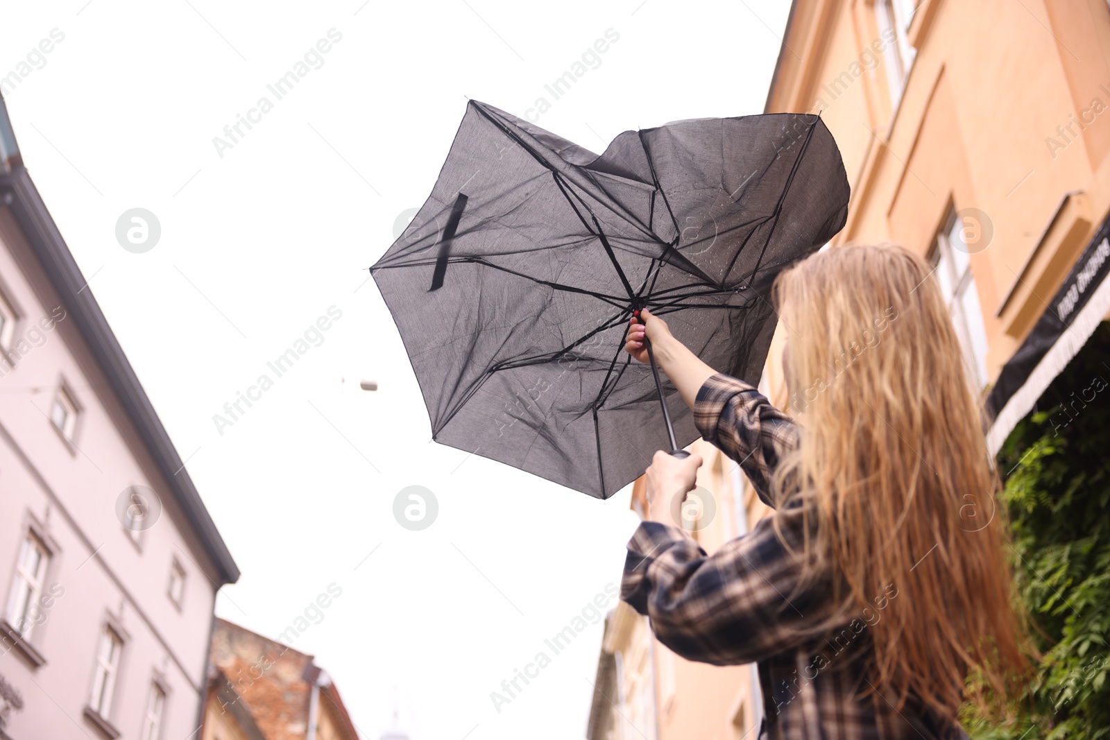 Woman with broken umbrella outdoors, low angle view Photo of Woman with broken umbrella outdoors, low angle view