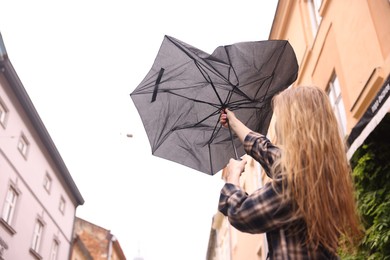 Photo of Woman with broken umbrella outdoors, low angle view