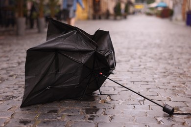 Photo of Broken umbrella on wet pavement outdoors, closeup