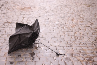 Photo of Broken umbrella on wet pavement outdoors. Space for text