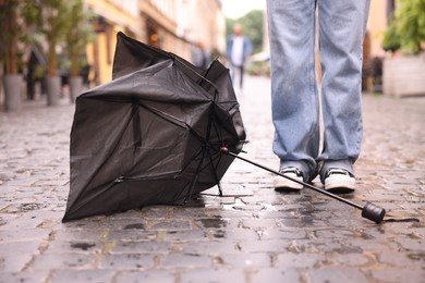 Photo of Woman and broken umbrella on wet pavement outdoors, closeup