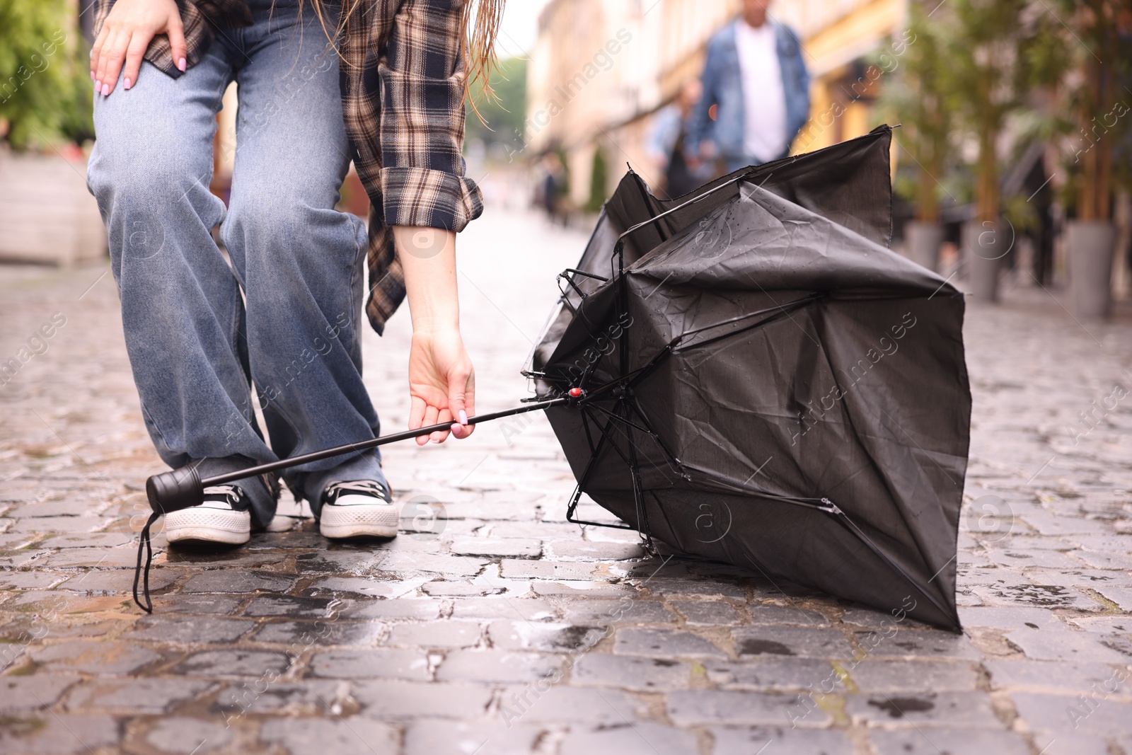 Woman taking broken umbrella on wet pavement outdoors, closeup Photo of Woman taking broken umbrella on wet pavement outdoors, closeup
