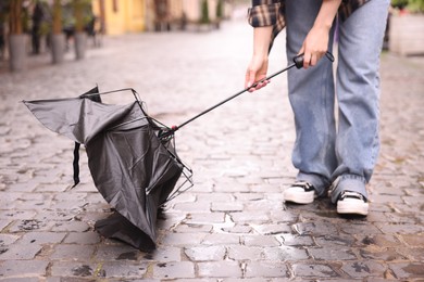 Photo of Woman with broken umbrella on wet pavement outdoors, closeup