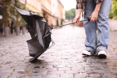 Photo of Woman with broken umbrella on wet pavement outdoors, closeup