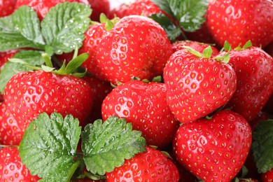 Photo of Fresh ripe strawberries and green leaves as background, closeup