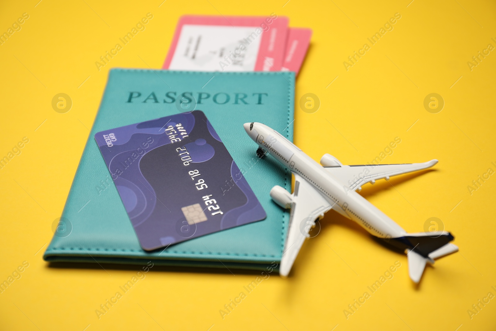 Passport with tickets, credit card and airplane model on yellow background, closeup Photo of Passport with tickets, credit card and airplane model on yellow background, closeup