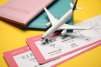 Photo of Passports with tickets and airplane model on yellow background, closeup