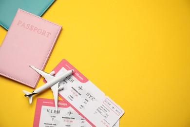 Photo of Passports with tickets and airplane model on yellow background, flat lay. Space for text