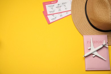 Photo of Passport, airplane model, hat and tickets on yellow background, flat lay. Space for text