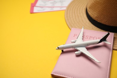 Photo of Passport, airplane model, hat and tickets on yellow background, closeup. Space for text