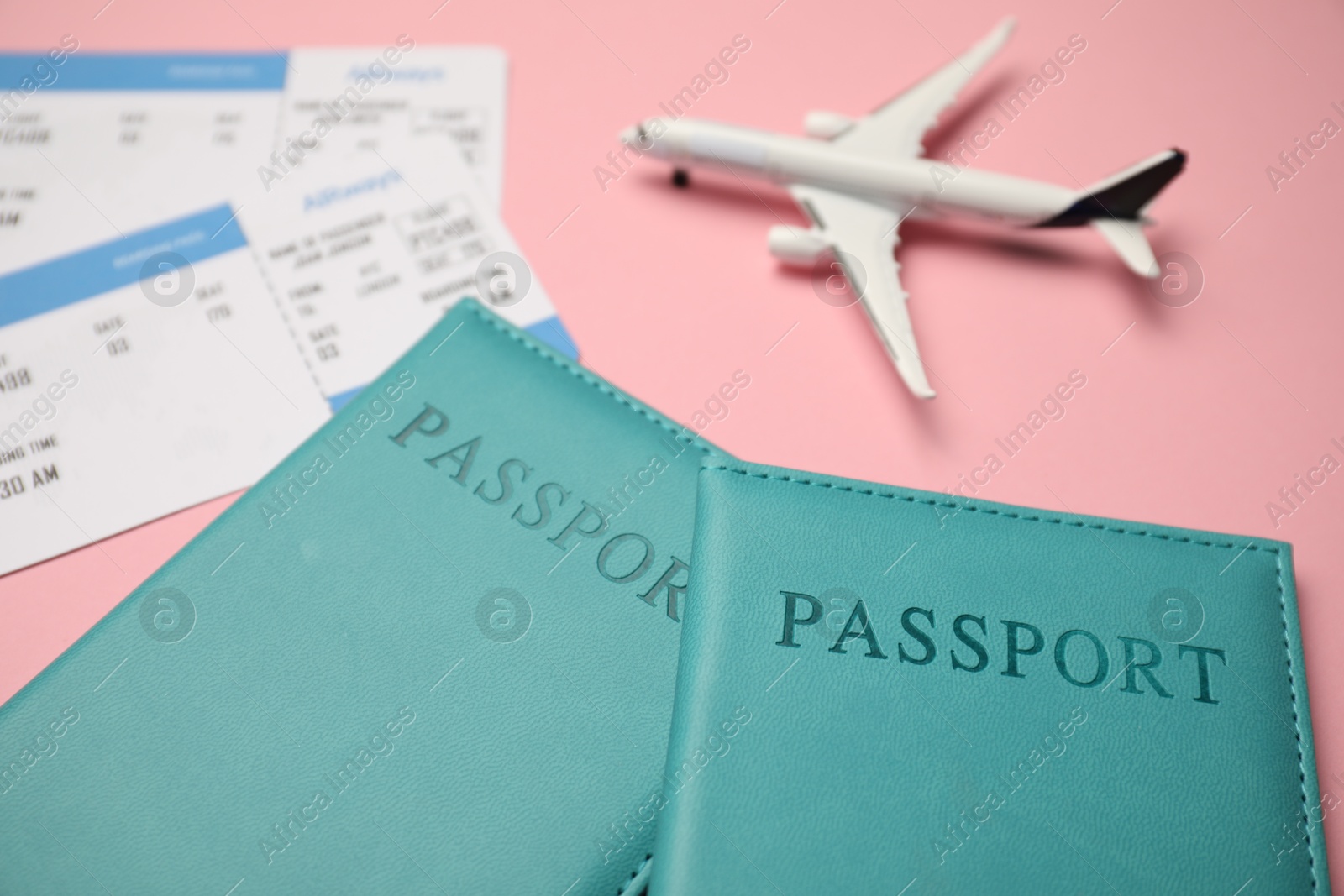 Passports with tickets and airplane model on pink background, closeup Photo of Passports with tickets and airplane model on pink background, closeup