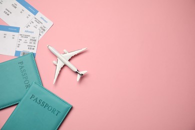 Photo of Passports with tickets and airplane model on pink background, flat lay. Space for text