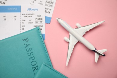 Photo of Passports with tickets and airplane model on pink background, flat lay