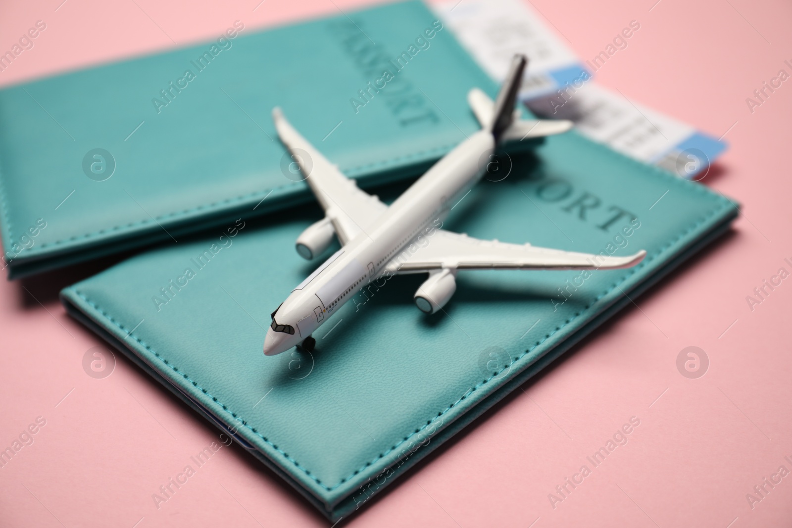Photo of Passports with tickets and airplane model on pink background, closeup