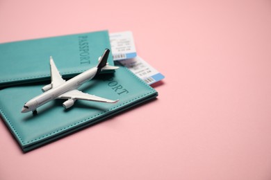 Photo of Passports with tickets and airplane model on pink background. Space for text