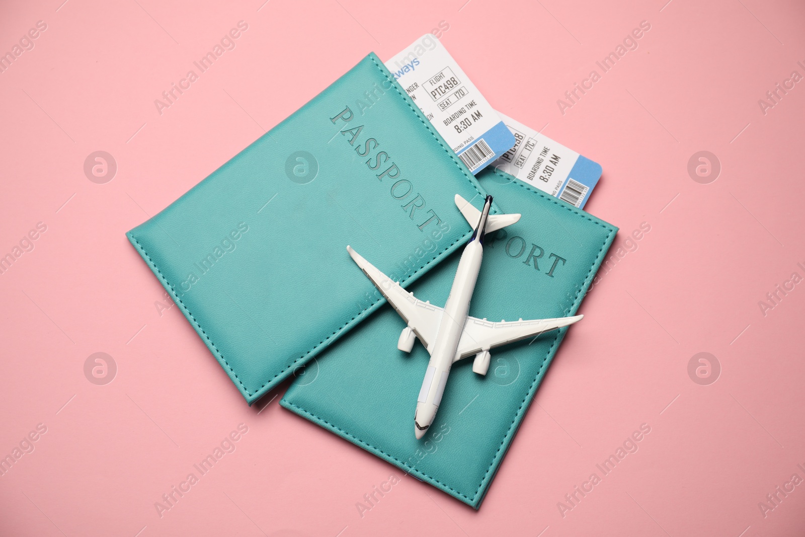Passports with tickets and airplane model on pink background, top view Photo of Passports with tickets and airplane model on pink background, top view