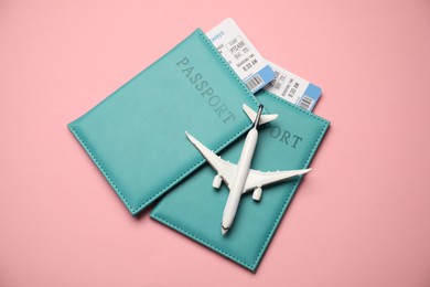 Photo of Passports with tickets and airplane model on pink background, top view