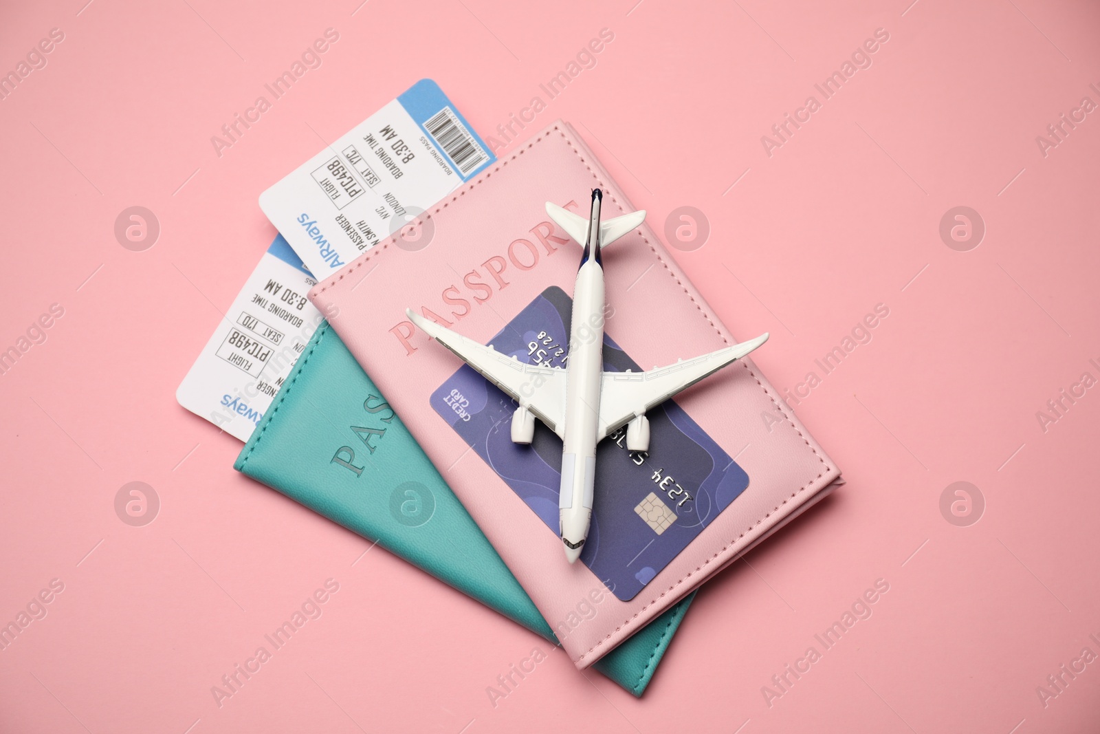 Passports with tickets, credit card and airplane model on pink background, top view Photo of Passports with tickets, credit card and airplane model on pink background, top view