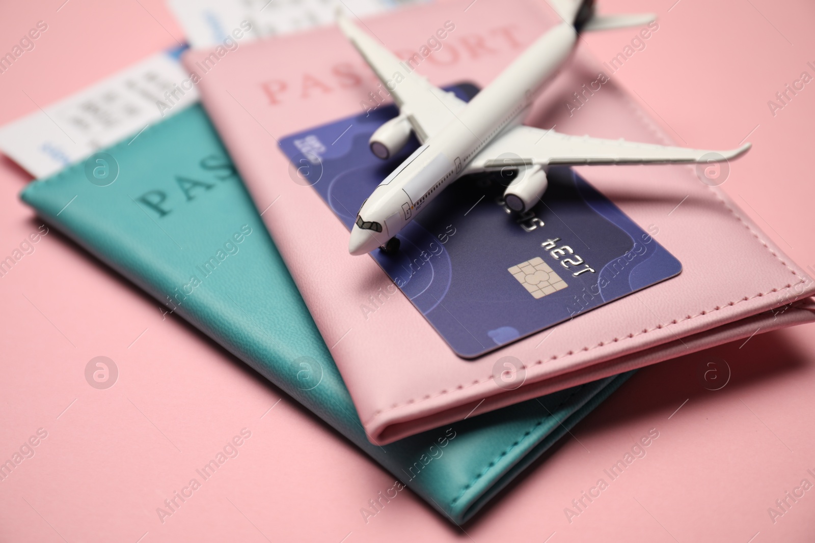 Passports with tickets, credit card and airplane model on pink background, closeup Photo of Passports with tickets, credit card and airplane model on pink background, closeup