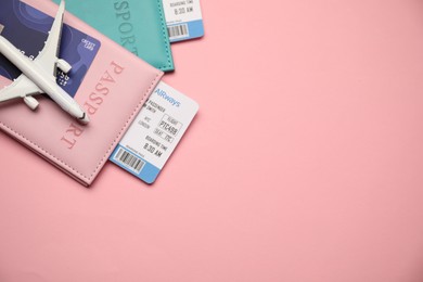 Photo of Passports with tickets, credit card and airplane model on pink background, top view. Space for text