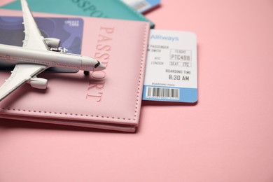 Photo of Passports with tickets, credit card and airplane model on pink background, closeup
