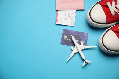 Photo of Passport with ticket, credit card, airplane model and shoes on light blue background, flat lay. Space for text