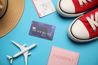 Photo of Passport with ticket, credit card, airplane model, hat and shoes on light blue background, flat lay