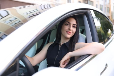 Photo of Woman behind steering wheel of modern car, view from outside